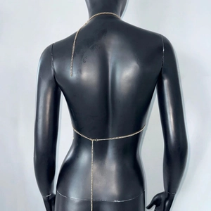 Detalle de cadena corporal dorada con pedrería y diseño de cuello halter y cintura para mujer