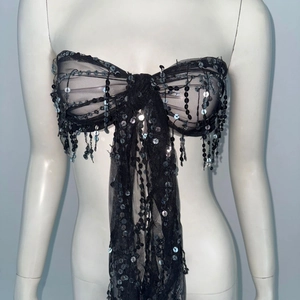 Detail of black mesh sequin tube top featuring butterfly bow design and shimmering tassels