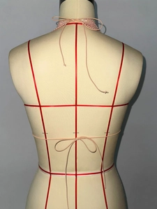 Vue arrière du haut dos nu en perles roses avec lacets sur un mannequin de couture