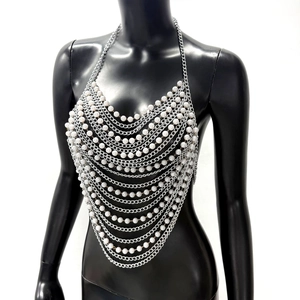 Detailed close-up of layered faux pearls and silver metal chain link harness top
