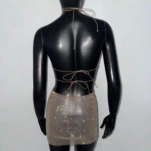 Détail de sequins dorés et strass brillants sur une mini robe dos nu à bretelles nouées