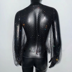 Détail d'un haut noir à manches longues en résille avec des strass colorés scintillants