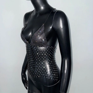 Detailed view of the sparkling rhinestones and open fishnet mesh on a black party vest