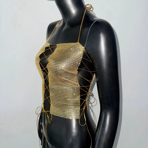 Macro detail of golden metal mesh halter top with adjustable crisscross chain ties