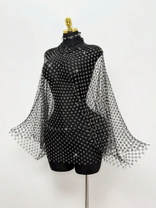 Dettaglio macro di un abito a rete nero con strass argentati brillanti ed effetti a stella