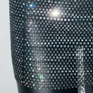 Vista macro del tessuto a rete nero con strass quadrati argentati e cristalli luccicanti