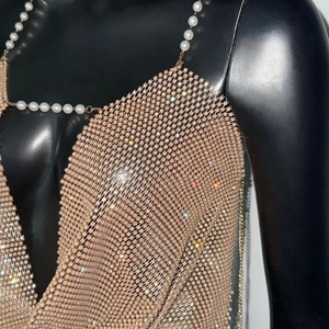 Détail du haut en maille strass or rose avec bretelles en perles blanches et grille en métal