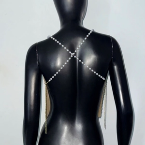 Détail de perles blanches et chaîne de corps en maille dorée sur le dos d'un modèle