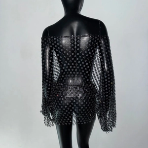 Dettaglio dell'abito in rete nera con spalle scoperte e decorazioni floreali in paillettes