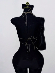 Macro shot of silver body chain with rhinestones and tie-up bow on a black mannequin