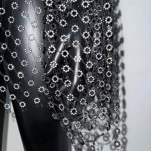 Dettaglio del tessuto a rete nera con motivi floreali in strass scintillanti e texture