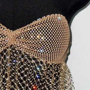 Close-up of sparkling beads woven into a mesh corset top for beachwear on a black mannequin