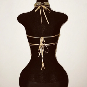 Haut de corps à perles dorées avec dos nu et détails de laçage sur un mannequin