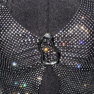 Détail du haut avec décolleté en V orné de strass denses et d'une boucle métallique