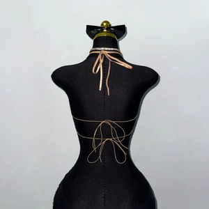 Détail du haut dos nu à lacets croisés avec collier en strass de couleur abricot