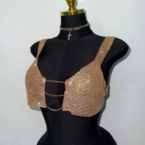 Close-up of champagne gold rhinestone top featuring metal chains and a cross pendant charm
