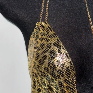 Détail d'un caraco à paillettes léopard avec fines bretelles en chaîne dorée