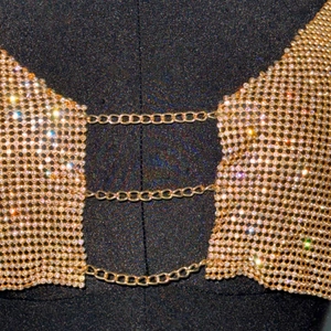 Macro detail of gold metal mesh top with sparkling rhinestones and triple chain links
