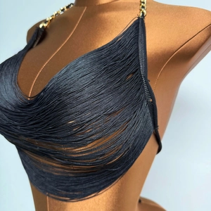 Dettaglio del top nero con frange e spalline a catena dorata in stile boho chic