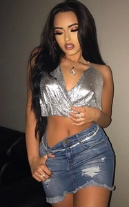 Detail of silver metallic sequin halter top paired with distressed denim skirt and waist chain