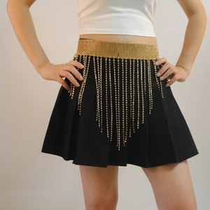 Macro detail of golden rhinestone fringe belt with shimmering tassels on a black skirt