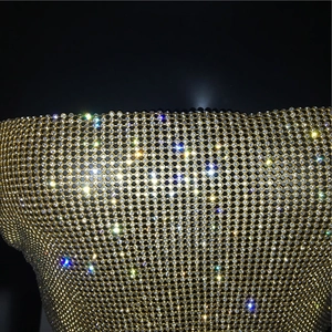 Makro-Detail von luxuriösem Goldmetall-Mesh-Oberteil mit schimmernden Strasssteinen