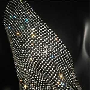 Macro detail of high-density silver rhinestones on a black party top with sparkling light