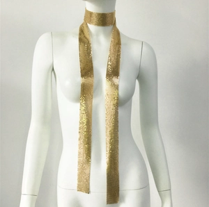 Dettaglio della lunga collana a sciarpa in maglia metallica dorata con paillettes su manichino