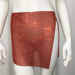 Détail d'une mini-jupe orange vif en résille de strass avec fente latérale scintillante
