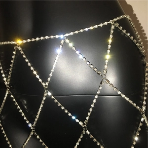 Detail of silver rhinestone mesh body chain with sparkling diamond grid on black background