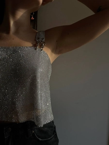 Detail of silver rhinestone mesh crop top with metallic texture and buckle straps