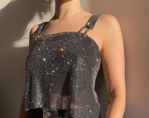 Detailed macro view of rhinestone shoulder straps and metal buckle on the sparkly crop top