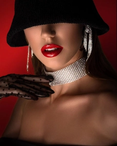 Nahaufnahme des breiten Strass-Chokers und langer Fransenohrringe auf rotem Hintergrund
