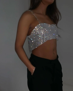 Gros plan du crop top argenté scintillant en strass reflétant des lumières colorées