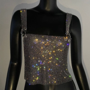 Macro detail of sparkly rhinestone mesh crop top with thin straps and metal ring buckles
