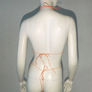 Detailansicht der Rückseite des orangefarbenen Schnürbikinis mit Kreuzgurten auf Schaufensterpuppe