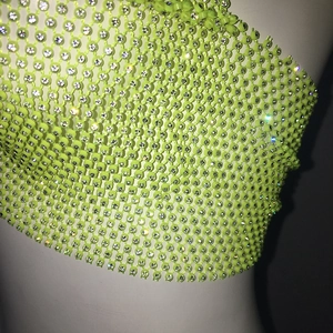 Detailed close-up of fluorescent yellow fishnet crop top with glittering rhinestones