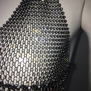 Close-up of black fishnet bikini top with sparkling rhinestones on white mannequin
