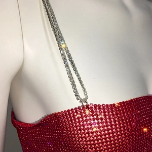 Gros plan sur le tissu en maille de strass rouges avec de fines bretelles en cristal