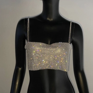 Détail d'un top court argenté en strass montrant des cristaux brillants et fines chaînes