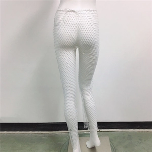 Gros plan du pantalon en résille blanche orné de strass brillants et lien à la taille