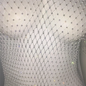 Close-up of white fishnet fabric with embedded sparkling rhinestones for women's tops
