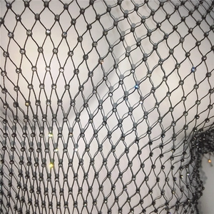Gros plan du tissu résille noir orné de strass scintillants et texture de maille fine