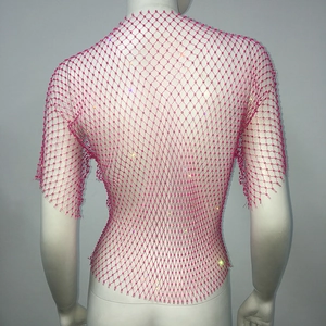 Macro detail of pink fishnet mesh top featuring sparkling rhinestones on an empty mannequin