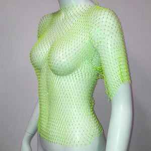 Detail of neon green fishnet mesh top with sparkling rhinestones on fabric nodes