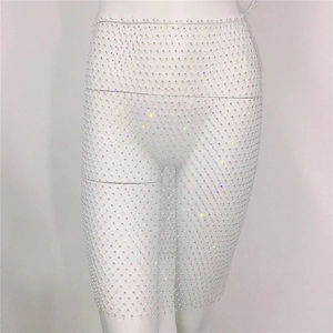 Détail d'une jupe en maille blanche avec des strass brillants et des bords à franges