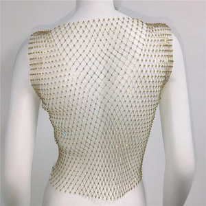 Détail du gilet en maille strass dorée montrant le motif de grille et les cristaux brillants