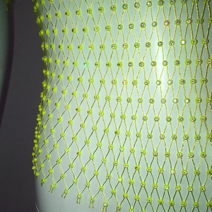 Macro detail of neon yellow fishnet top featuring sparkling rhinestone grid accents