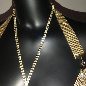 Detailed close-up of golden rhinestone body chain with mesh webbing and metal clasps