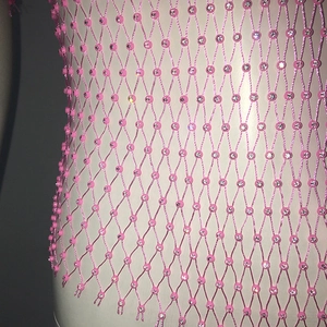 Detail of pink mesh top with sparkling rhinestones and hollow diamond pattern texture